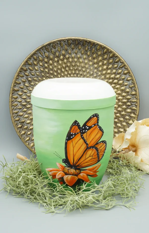 Bio Urne grün mit orangenem Schmetterling und dekorativem Hintergrund