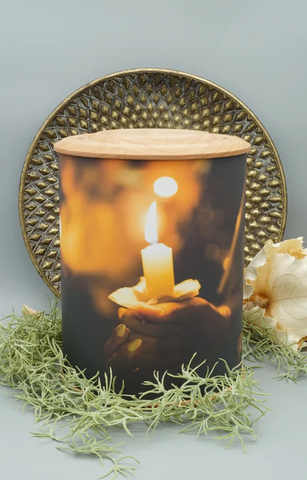 Fotourne mit Holzboden und Holzdeckel mit einer Hand die eine brennende Kerze hält bedruckt mit dekorativem Hintergrund