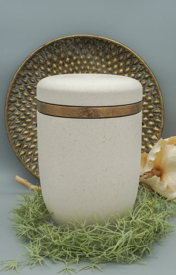 Bio Urne aus Muschelkalk in weiß mit goldenem Streifen und dekorativem Hintergrund